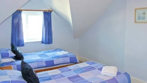 Ein Schlafzimmer mit zwei Betten, einem Fenster mit Vorhängen und einem gerahmten Bild an der Wand.
