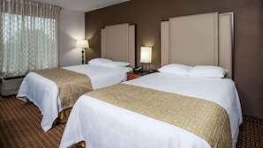 Ein Hotelzimmer mit zwei Betten, einem großen Fenster mit Vorhängen und einem Nachttisch mit Lampe.