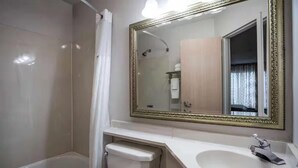 Ein Badezimmer mit einer Badewanne, Toilette, Waschbecken und einem großen Spiegel mit dekorativem Rahmen.