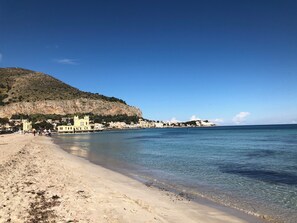 Una playa con aguas cristalinas, una orilla arenosa y edificios a lo largo de la costa.