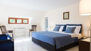 Ein Schlafzimmer mit einem großen Bett, einem Schreibtisch, zwei Stühlen und einem Fenster mit Blick.