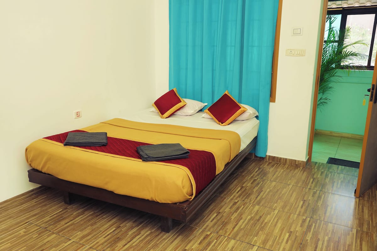 A neatly made bed with a yellow and red bedspread, two pillows, and a folded towel.