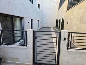 A narrow alleyway with a gated entrance, flanked by white walls and a black metal gate. - Family-Friendly & Warm  2 bedroom apartment  . Best for vacationers (Amman)