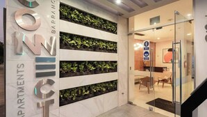 Un interior moderno con un jardín vertical y un área de recepción con puertas de vidrio.