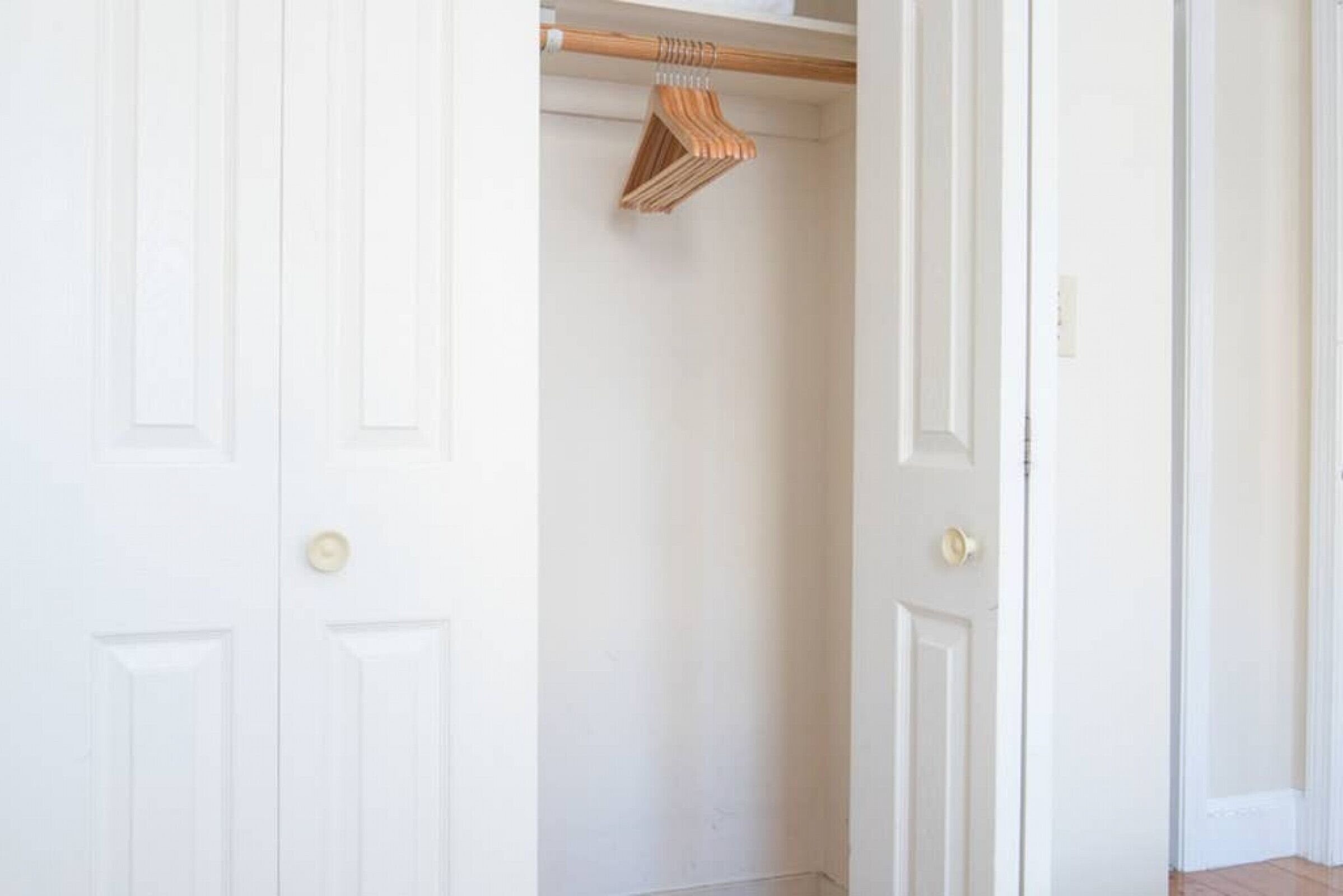 Una puerta blanca con un colgador de madera y un pequeño objeto blanco en el pomo.