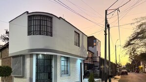 Una moderna casa a due piani con facciata curva, ampie finestre e un piccolo giardino antistante.