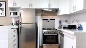 Una cucina moderna con mobili bianchi, un frigorifero in acciaio inossidabile, un forno Bosch e un microonde.