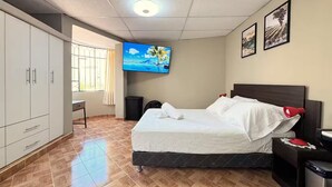 Una camera d'albergo con un letto, una televisione, una scrivania e un armadio.