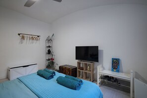 A bedroom with a bed, a TV, a shelf with a picture frame, and a radiator. - [Colosseum - Esquilino] Ikigai Peaceful Apartment (Roma)