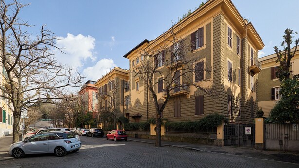 Une rue bordée de bâtiments historiques, avec une chaussée pavée et des voitures garées.