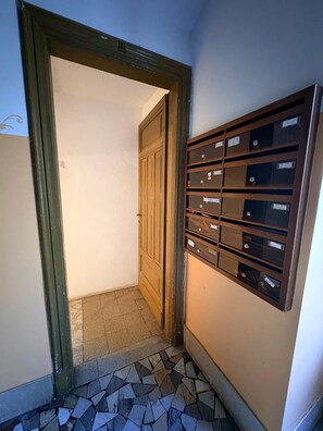 Ein Flur mit Fliesenboden, einer Holztür und einem an der Wand befestigten Briefkasten.
