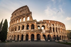 The Colosseum with multiple arches and a central entrance, surrounded by a cobblestone area. - [Colosseum - Esquilino] Ikigai Peaceful Apartment (Roma)