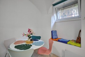 Ein Essbereich mit einem runden Tisch, Stühlen, einer Vase mit Blumen und einem Fenster mit Blick.