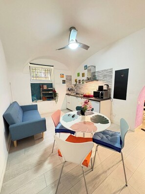 Ein modernes Wohnzimmer mit einem blauen Sofa, einem weißen Tisch mit originellem Design und einem Deckenventilator.