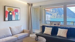 A modern living room with a sofa, a coffee table, and a painting on the wall. - Blue Vista Lugano Apt.616 by Interhome (Bissone)