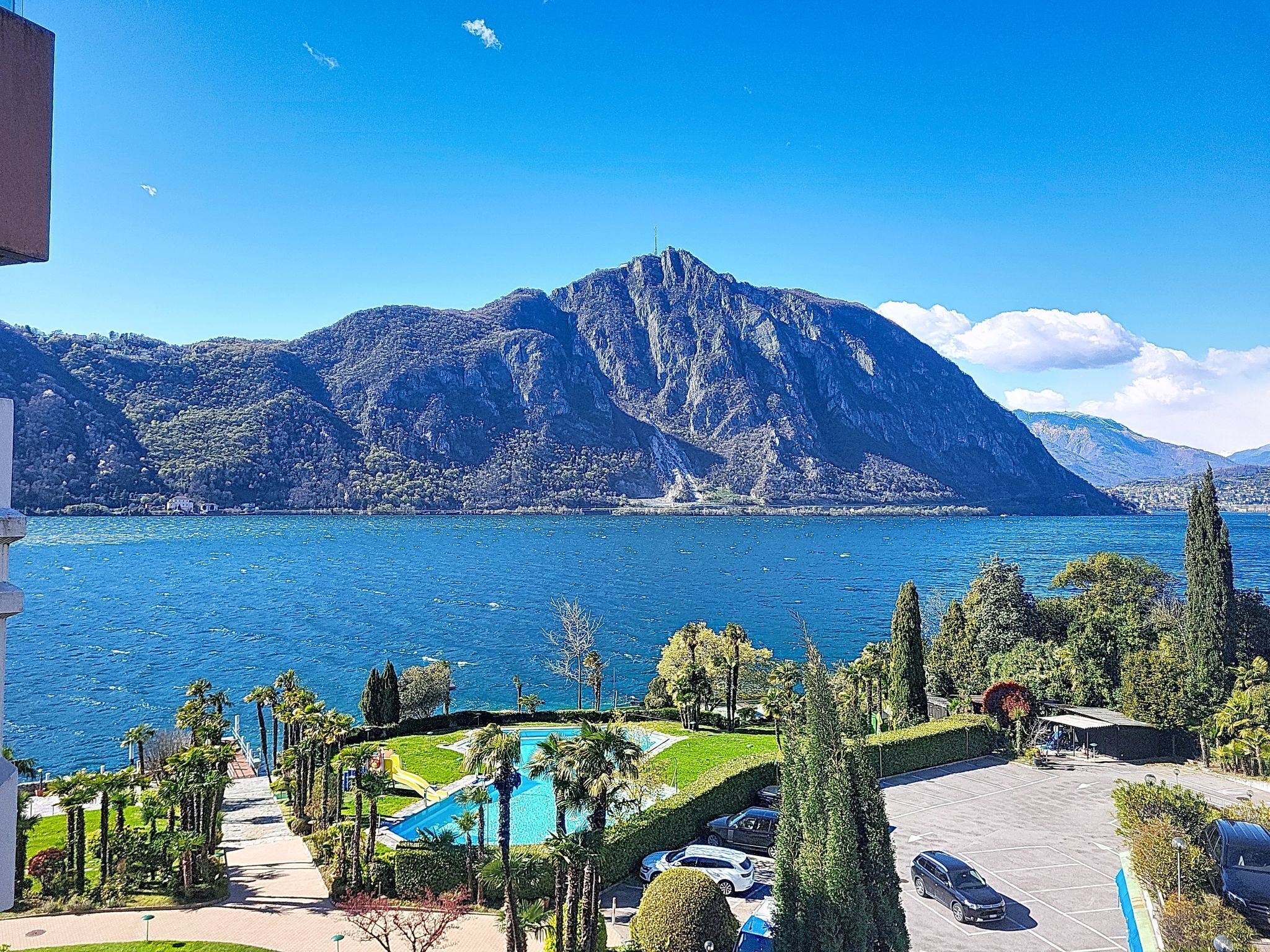 Vista a la montaña con piscina y zona de estacionamiento.