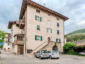 A multi-story building with a stone staircase leading to the entrance, a small balcony, and a car parked in front. - Tra gli Ulivi by Interhome (Riva del Garda)