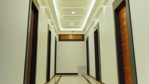 A hallway with a modern ceiling design, recessed lighting, and a polished floor. - Hotel KS Palace (Sarnath)
