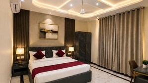 A modern bedroom with a large bed, marble flooring, and recessed ceiling lighting. - Hotel KS Palace (Sarnath)