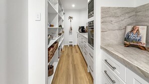 A modern kitchen with white cabinetry, a wooden floor, and a marble countertop. - The Lazy Pelican - Tea Gardens (Tea Gardens)