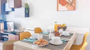 Un coin repas avec une table mise pour le petit-déjeuner, comprenant du pain, des fruits et des boissons.