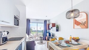 Une cuisine moderne avec un coin repas, une vue à travers des portes vitrées et une table à manger agrémentée de chaises jaunes.
