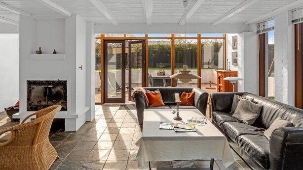A spacious living room with a fireplace, a sofa, a coffee table, and a view of the backyard through large glass doors. - "Talida" - 500m from the sea by Interhome (Skagen)