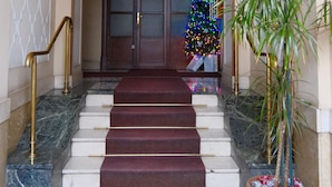 Ein prachtvoller Eingangsbereich mit einer Marmortreppe, einem Weihnachtsbaum und einer Topfpflanze.