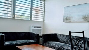 Ein Zimmer mit einer Couch, einem Holztisch und einem Gemälde an der Wand.