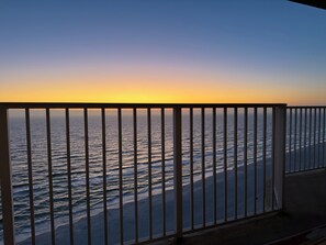 A balcony with a view of the ocean at sunset. - Brand new Boardwalk reno, king bed + bunks, perfect for couple or young family! (Panama City Beach)