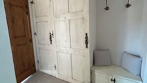 Quarto com porta deslizante, um banco com almofadas e um ventilador de teto.