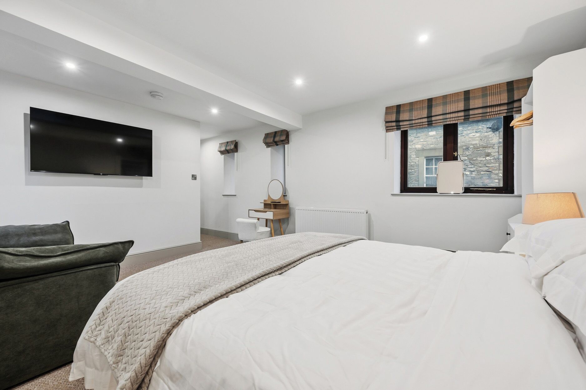 Une chambre moderne avec un grand lit, un téléviseur à écran plat, une fenêtre donnant sur un beau paysage et un petit bureau avec une chaise.