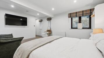 Une chambre moderne avec un grand lit, un téléviseur à écran plat, une fenêtre donnant sur un beau paysage et un petit bureau avec une chaise.