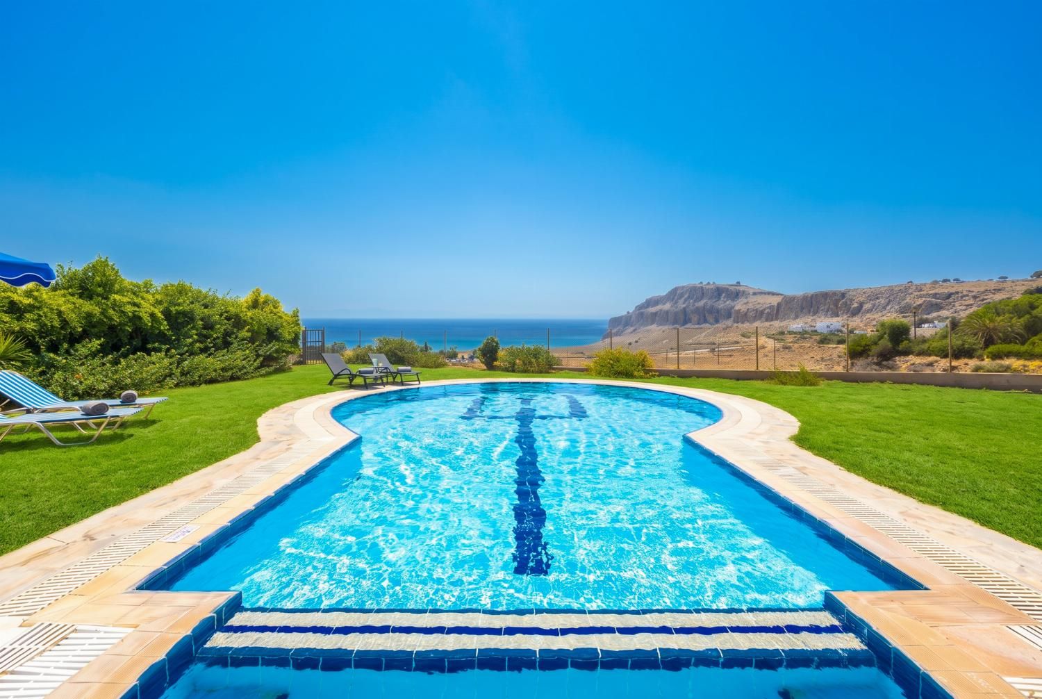 A swimming pool with a view of the ocean and hills.