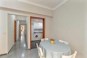 A hallway leading to a kitchen with a washing machine, a dining table with chairs, and a small plant on the table. - Vacation Home 'Gáldar-centro' with Private Terrace, Balcony, and Wi-Fi (Gáldar)