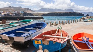 Un puerto costero con barcos amarrados, un muelle y montañas al fondo.