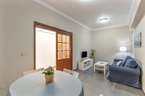 A living room with a round table, a sofa, a TV, and a door leading outside. - Vacation Home 'Gáldar-centro' with Private Terrace, Balcony, and Wi-Fi (Gáldar)