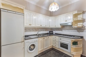 A kitchen with white cabinets, a washing machine, a microwave, and a stove. - Vacation Home 'Gáldar-centro' with Private Terrace, Balcony, and Wi-Fi (Gáldar)