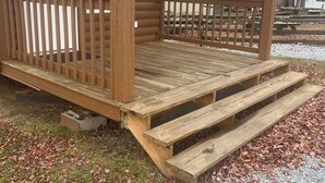 Een houten hut met een veranda, een deur en een brievenbus.