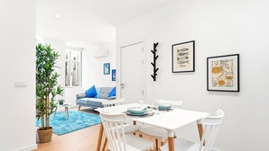 A modern dining area with a white table and chairs, a blue rug, and a potted plant. - GuestReady - The Olives - Blue (Coimbra)