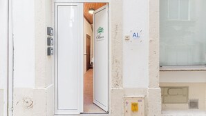 A hotel entrance with a white door, a small step leading inside, and a sign reading "The Olives Short-Term Rentals". - GuestReady - The Olives - Blue (Coimbra)
