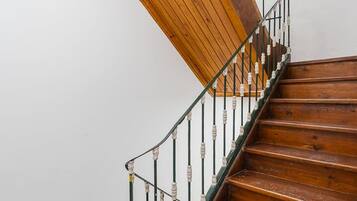 Un escalier en bois à la forme incurvée, doté de rampes en métal et adossé à un mur blanc.