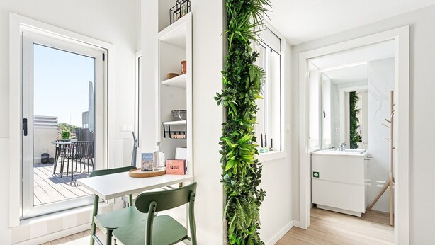 En modern inredning med ett matområde, en vertikal trädgård och utsikt över omgivningen.