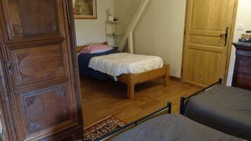 Un dormitorio con un armario de madera, una cama con edredón blanco, piso de madera y una alfombra pequeña.