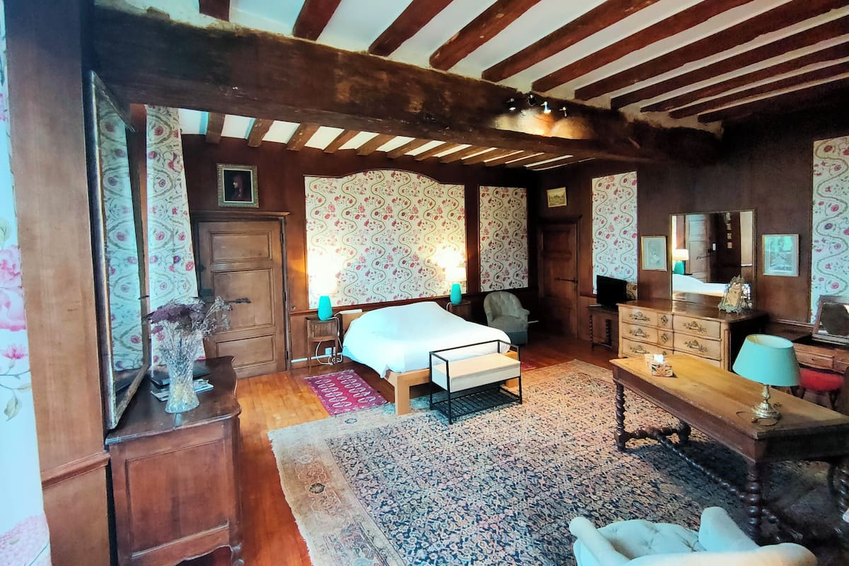 A traditional room with a bed, wooden furniture, and patterned wallpaper.