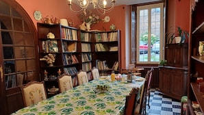A dining area with a table set for four, surrounded by bookshelves filled with books. - La Provosterie (Ahuillé)