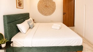 A neatly made bed with white bedding, a green upholstered headboard, and a decorative wall piece. - Cocon Vert Cozy Apartment in Sidi Bou Saïd (Sidi Bou Said)
