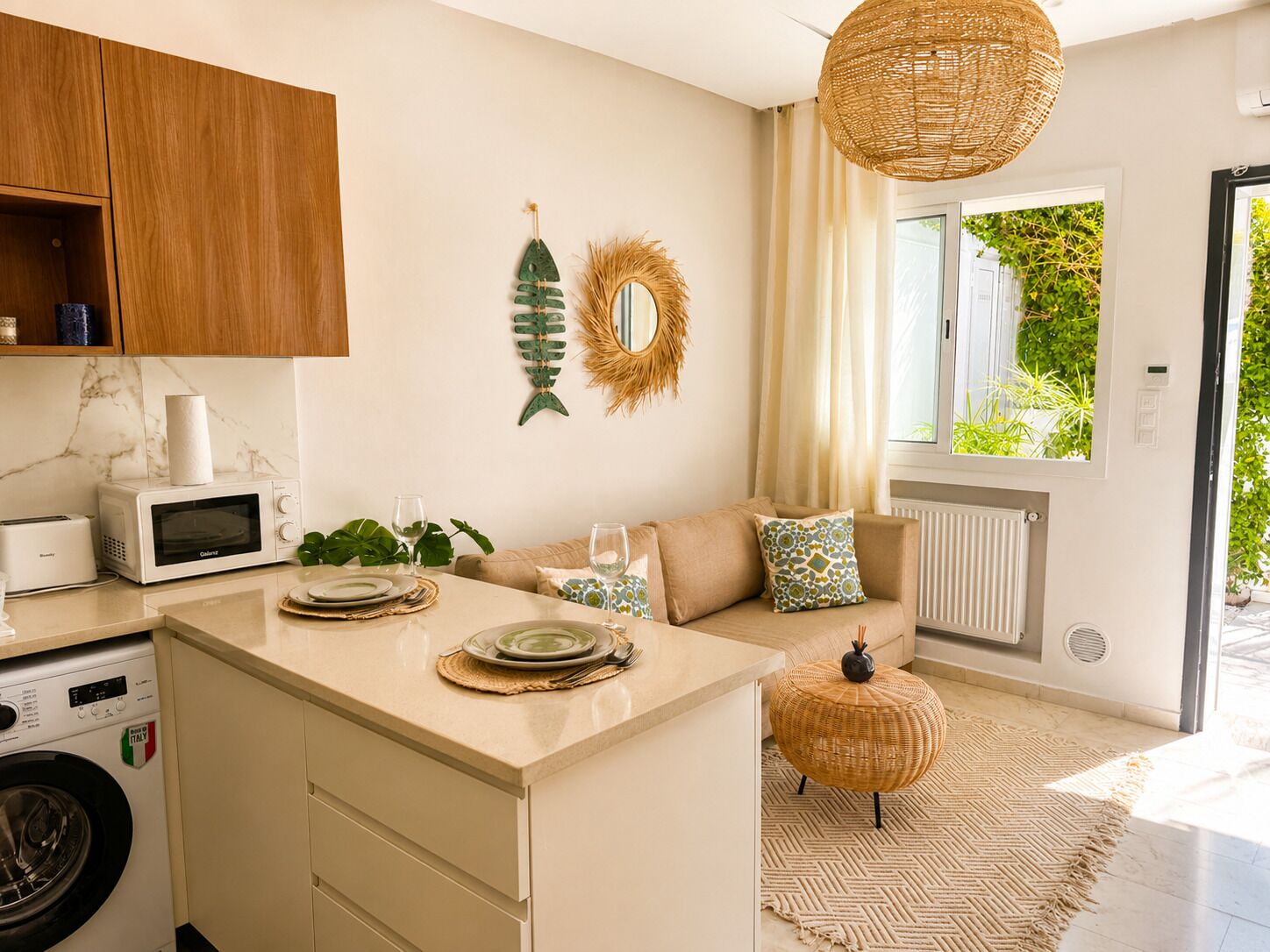 A modern kitchen with a central island, a microwave, a washing machine, and a dining area with a sofa and a round table.