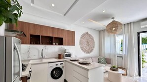 A modern kitchen with a built-in washing machine, wooden cabinets, and a large island. - Cocon Vert Cozy Apartment in Sidi Bou Saïd (Sidi Bou Said)