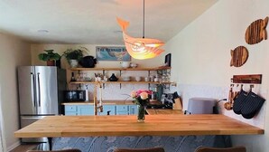 Ett modernt kök med en köksö i trä, barstolar och en hängande lampa.